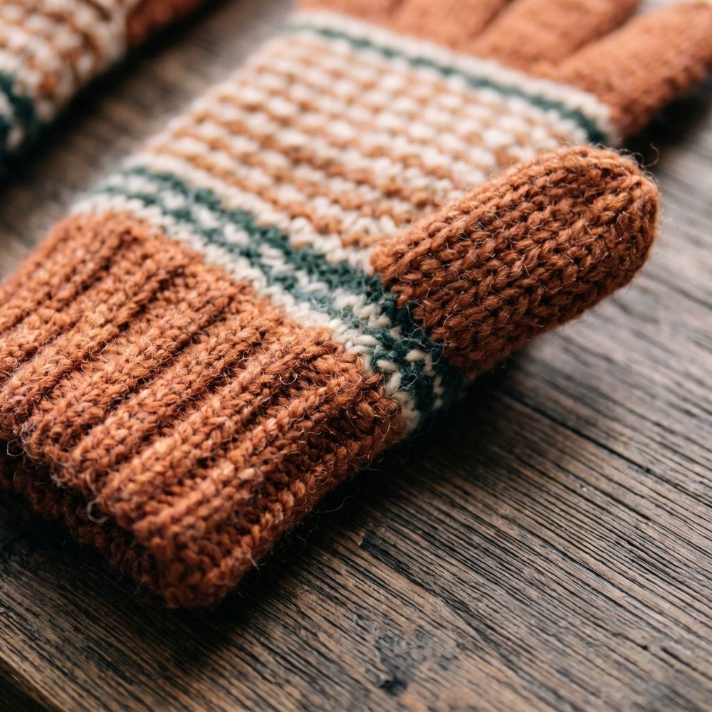 A close-up photo of rust-orange fingerless gloves with green stripes