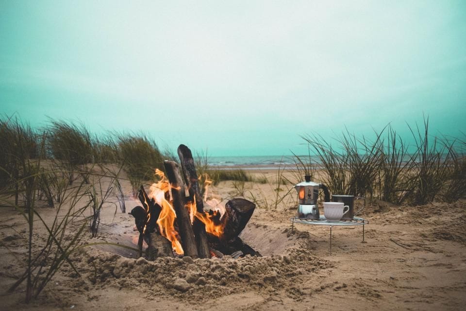 A small campfire burning on a sandy beach