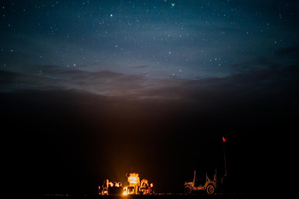 A tiny campfire under a sky full of stars