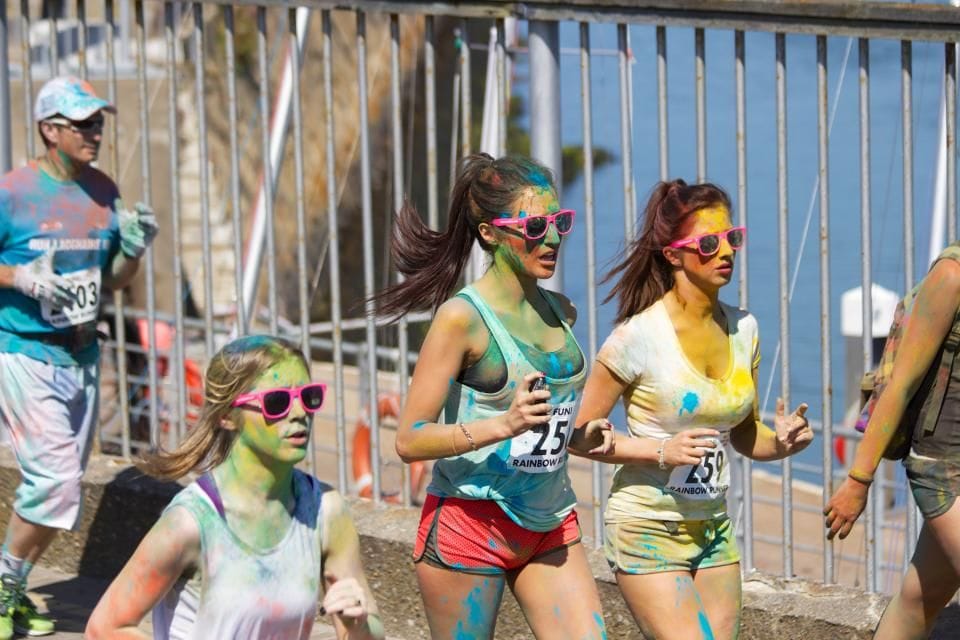 Three runners in colorful sunglasses laughing as they run