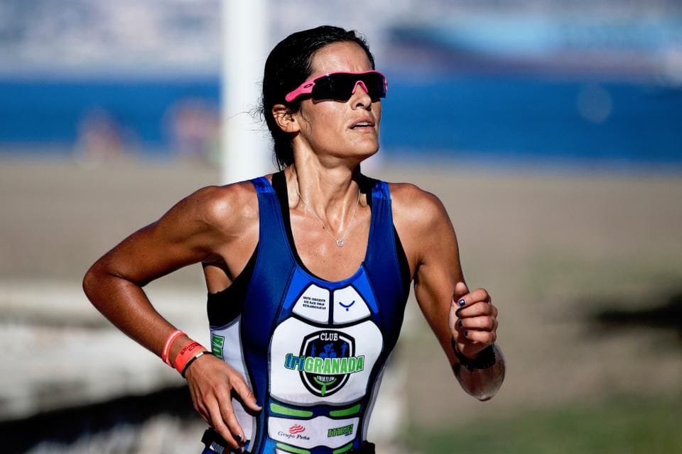 A runner in sunglasses and a club singlet mid-stride