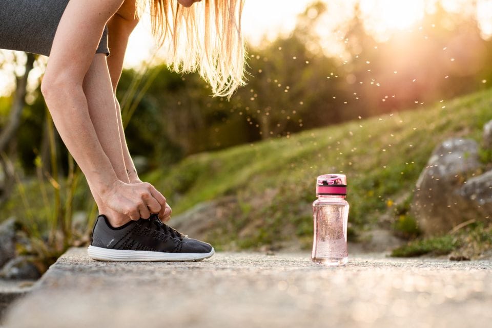 A runner tying a shoe on a grassy edge before the start