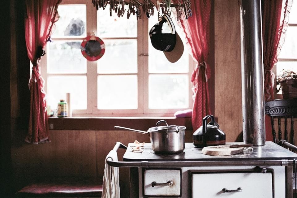 The old kitchen: a narrow room with a small window, an old stove and red curtains