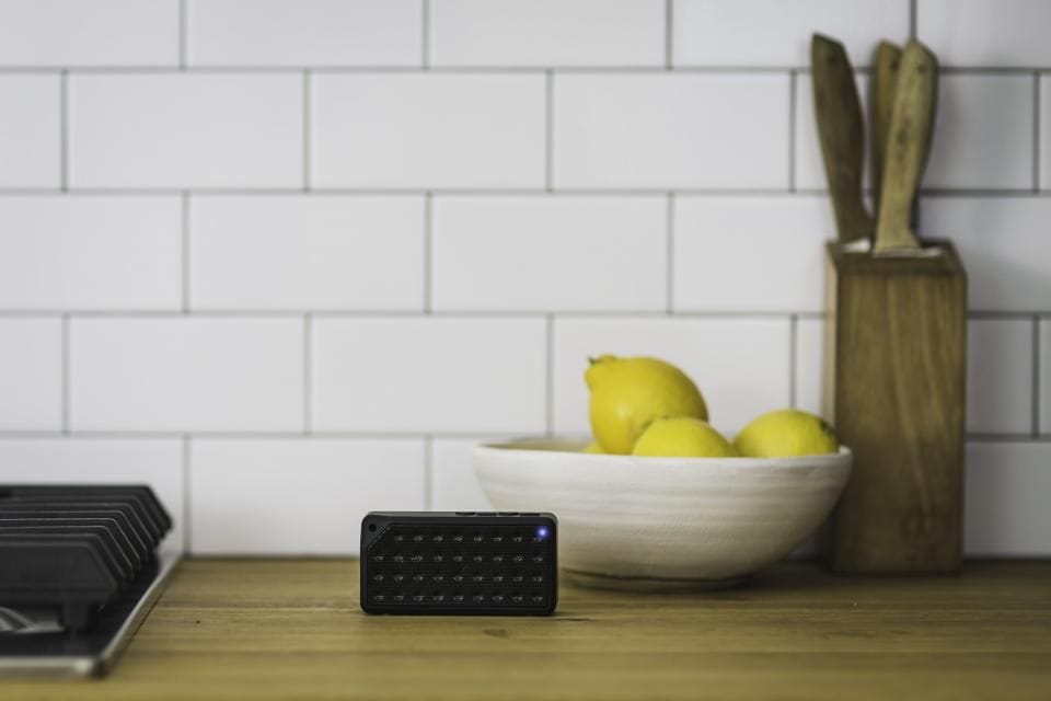 A counter against a white subway-tile wall with a bowl of lemons and a knife block