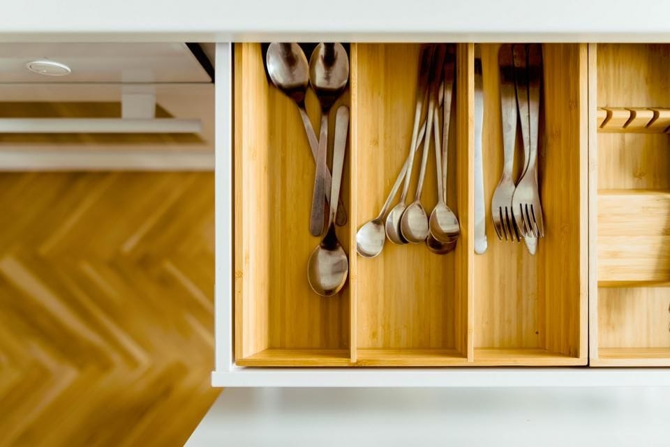 An open wooden drawer with a cutlery organizer