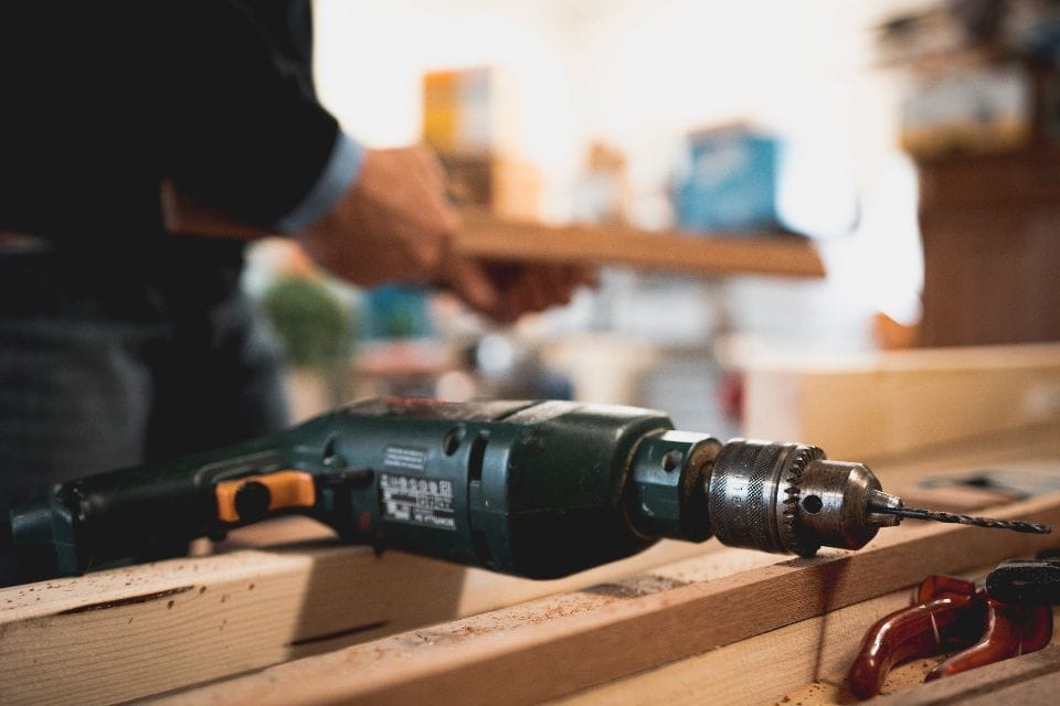 A cordless drill on a workbench in a workshop