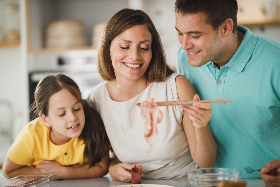 A family laughing as they cook together at the kitchen counter