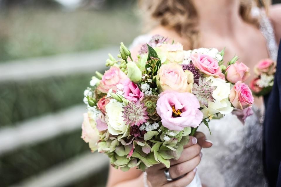 A bride holding a bouquet of pink peonies and sweet peas