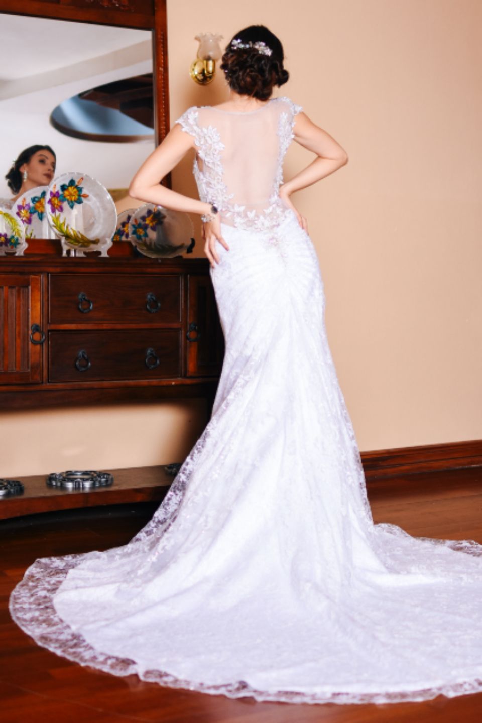 A bride seen from behind, her long lace train spread on the floor