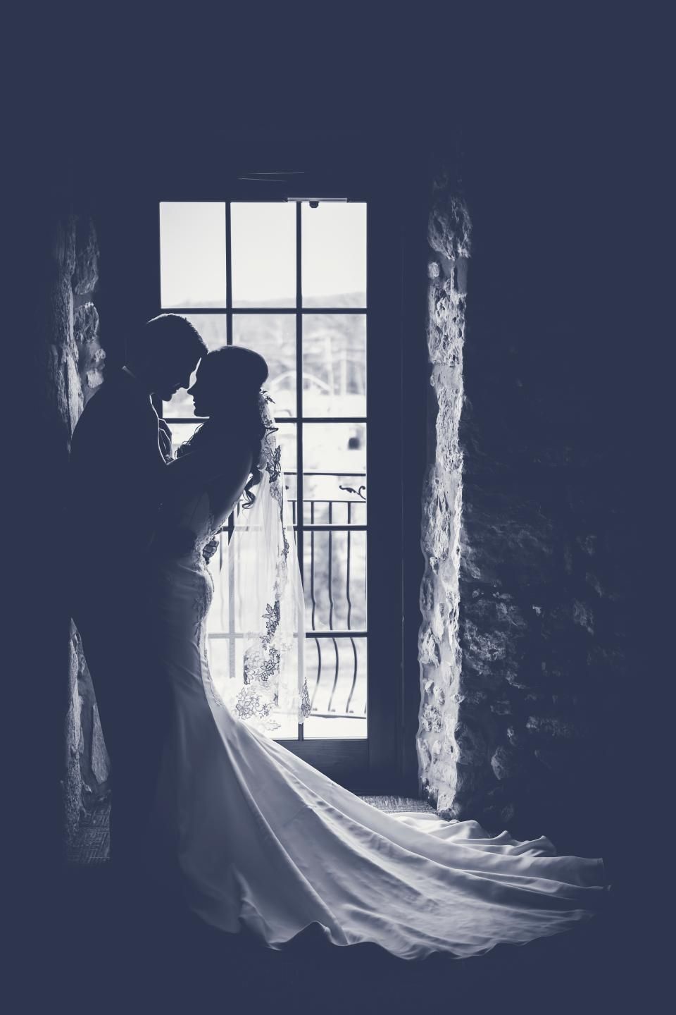 The silhouette of a bride and groom by a tall window