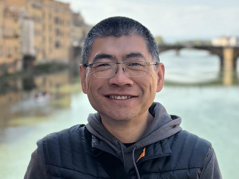 Frank Yang smiling beside a river
