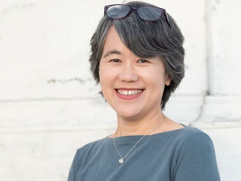 Olivia Lee smiling, sunglasses pushed up in her hair