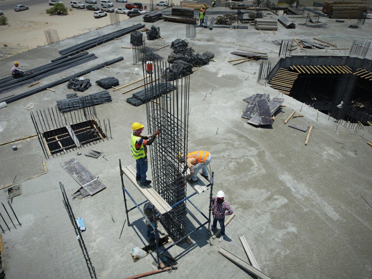 Workers tying rebar for a column on an open concrete deck