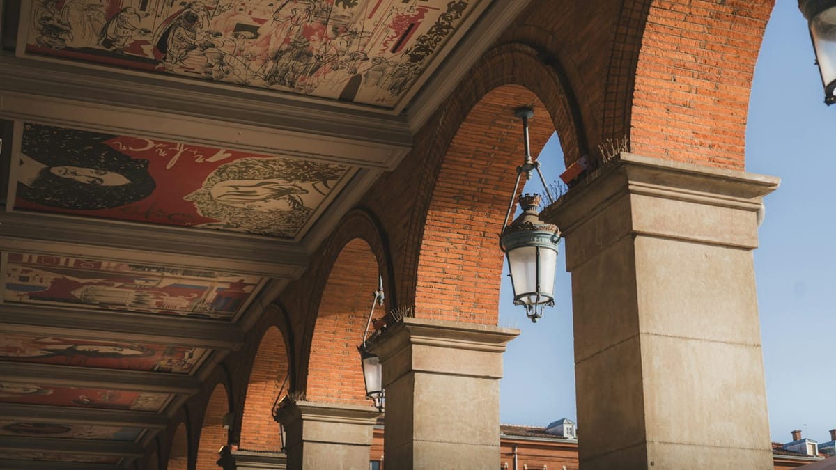 An arcade of old brick arches with hanging lanterns