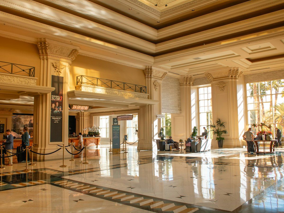 A sunlit hotel lobby with a coffered ceiling and a polished stone floor