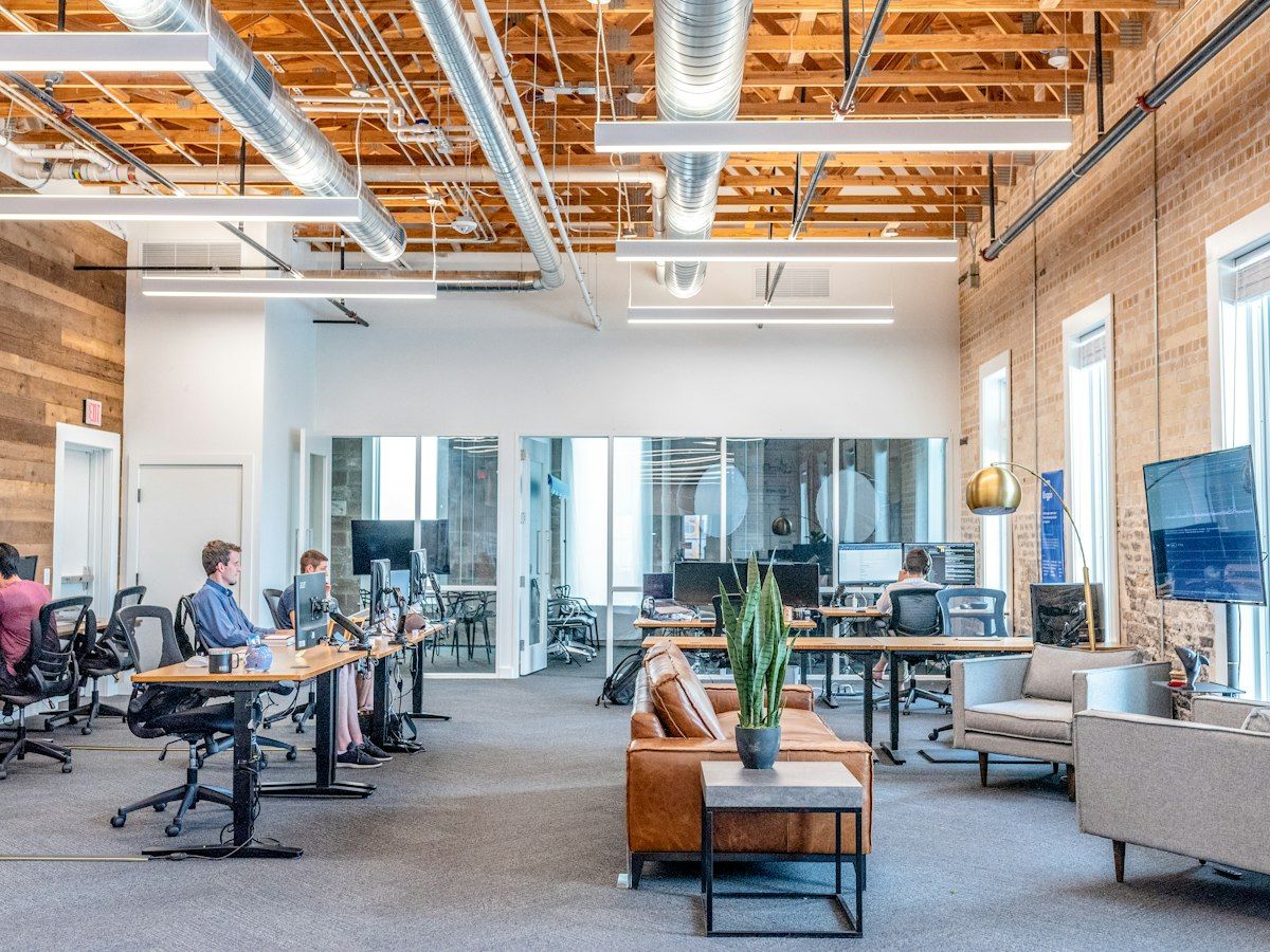 An open-plan office with exposed brick, timber ceiling and standing desks