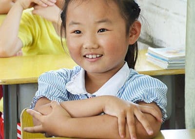A smiling girl at her school desk
