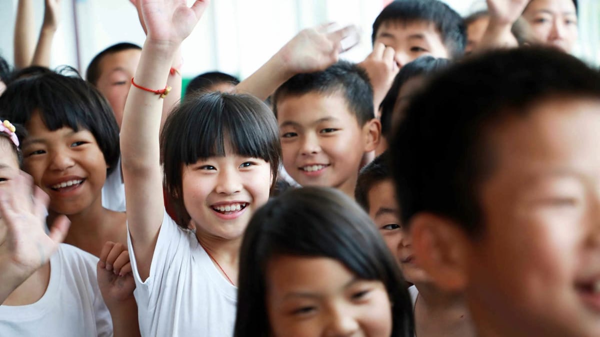 Children at a partner school waving and smiling