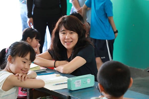 Founder Li Wei sitting with children at a school