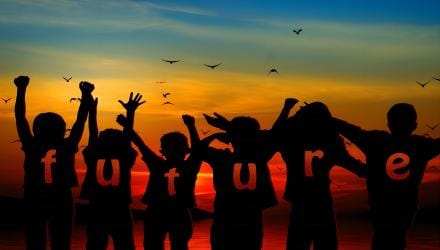 Children silhouetted against a sunset, arms raised, spelling out the word future