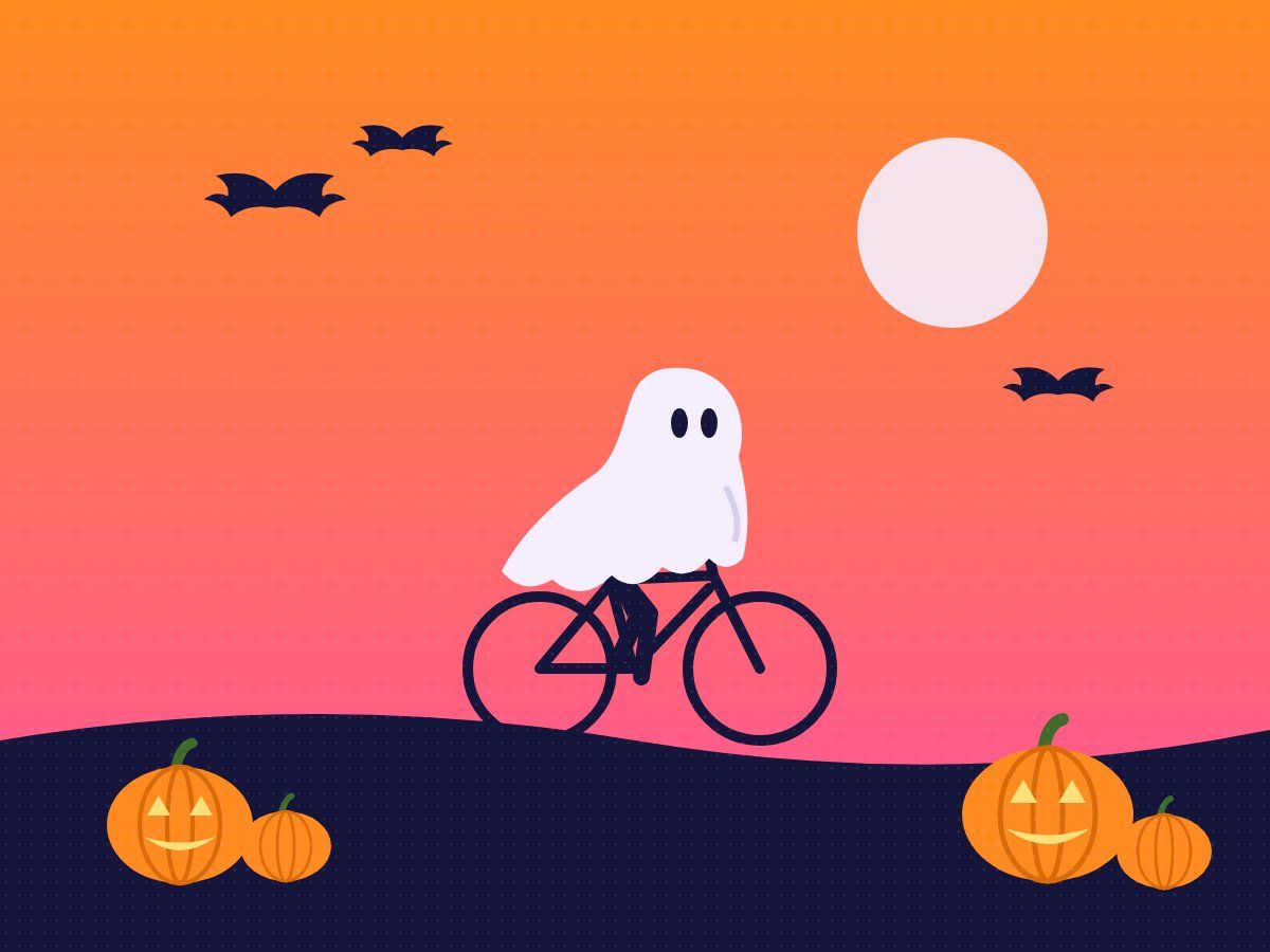 A rider dressed as a ghost on a bike beside pumpkins