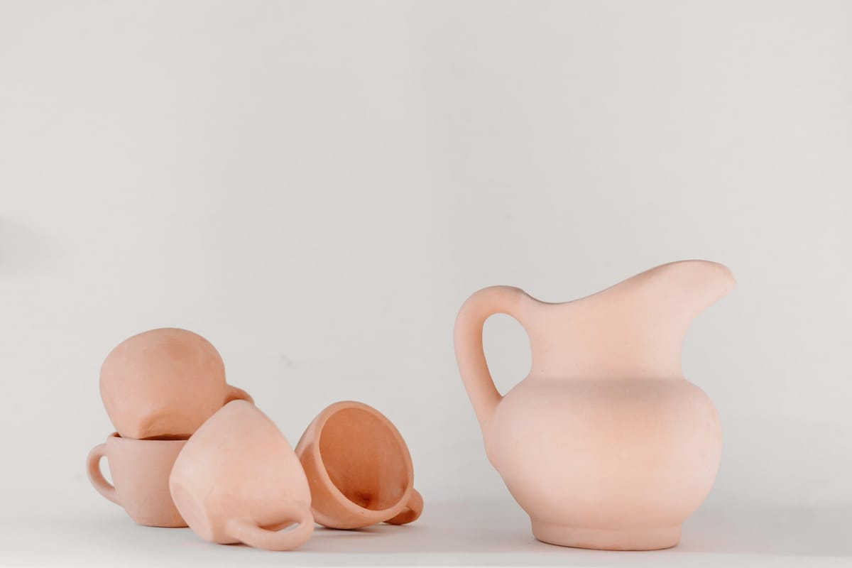Blush ceramic pitcher and cups on a soft white backdrop