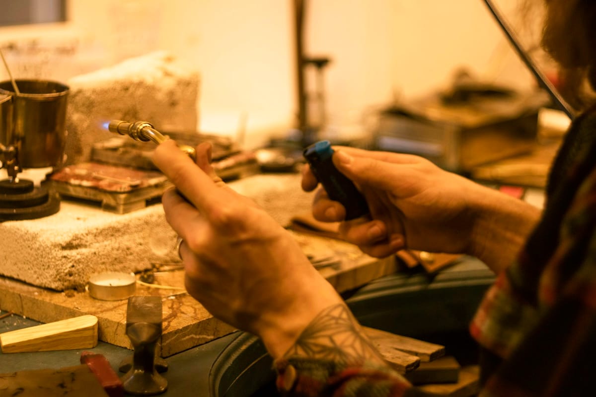 Hands working a small tool at a cluttered workbench