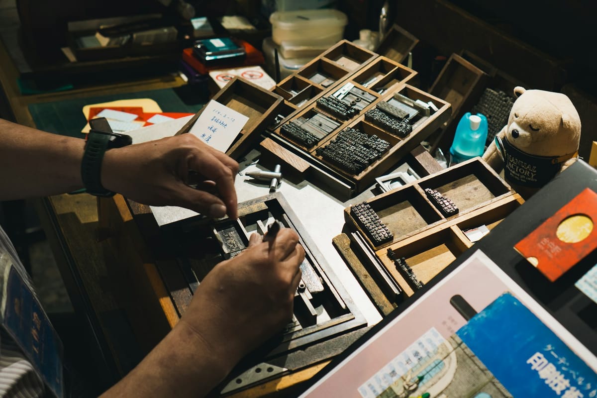 Hands setting type in a tray of letterpress blocks