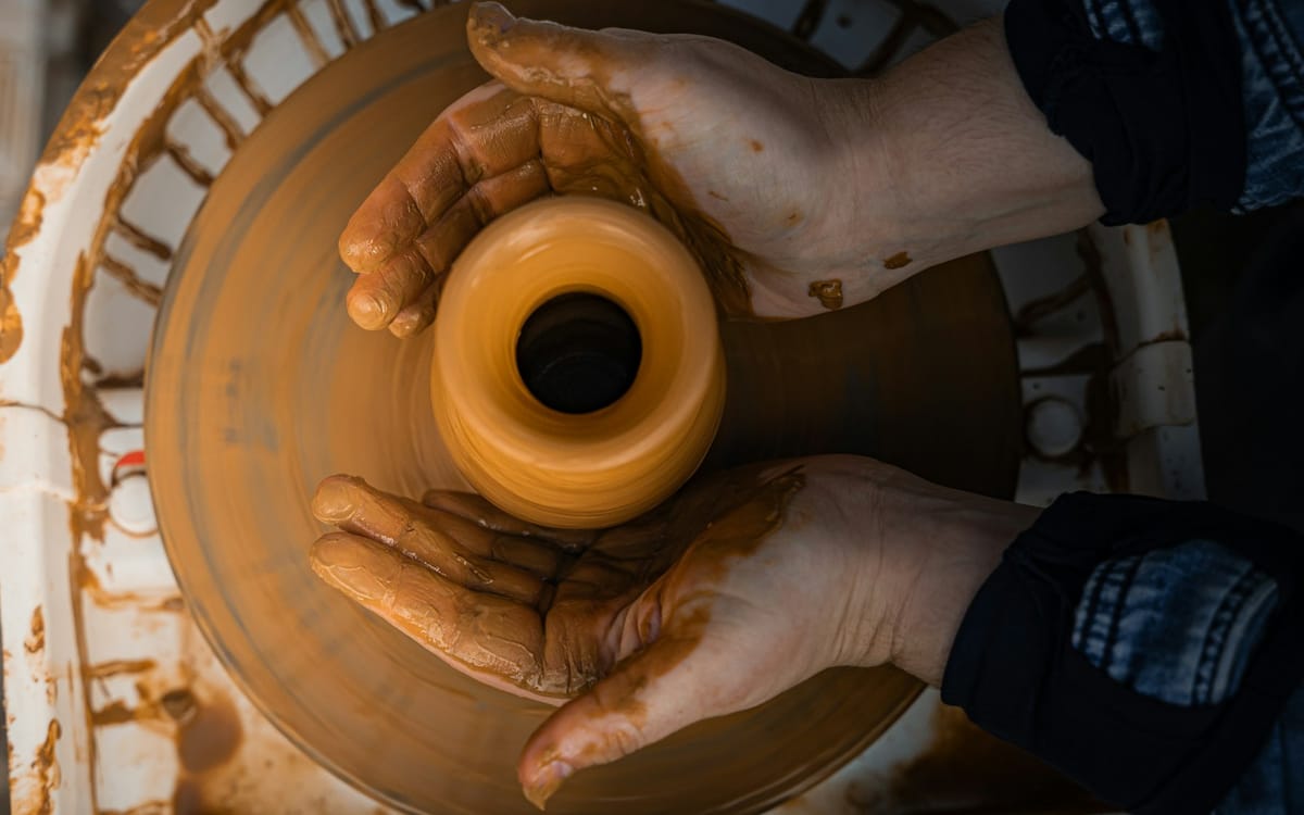 Hands shaping clay on a potter's wheel