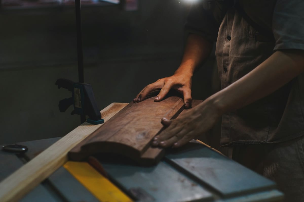 Hands guiding a board in a dim workshop