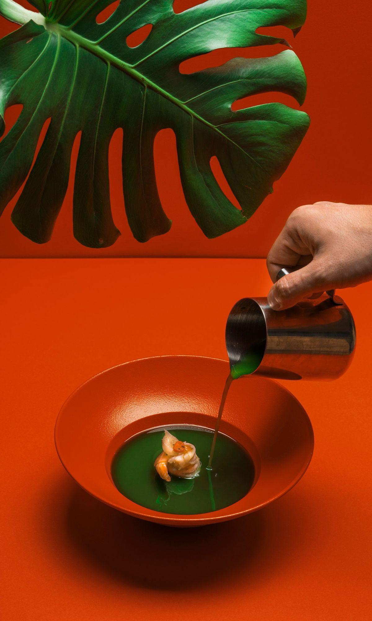 Sauce poured into a red bowl on an orange backdrop