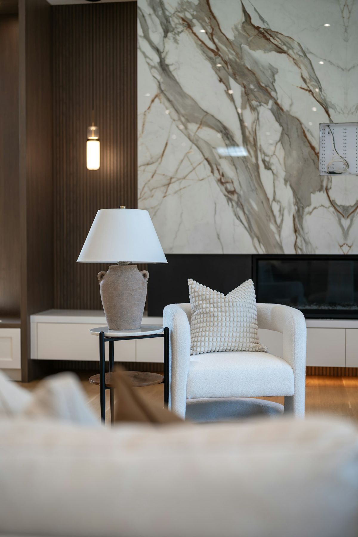 An armchair and table lamp in front of a marble wall