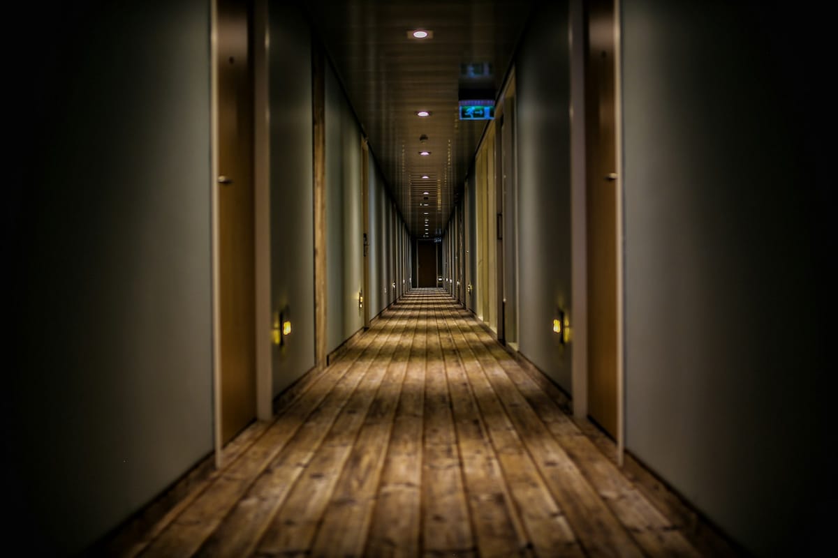 A long dark hotel corridor with warm wood flooring