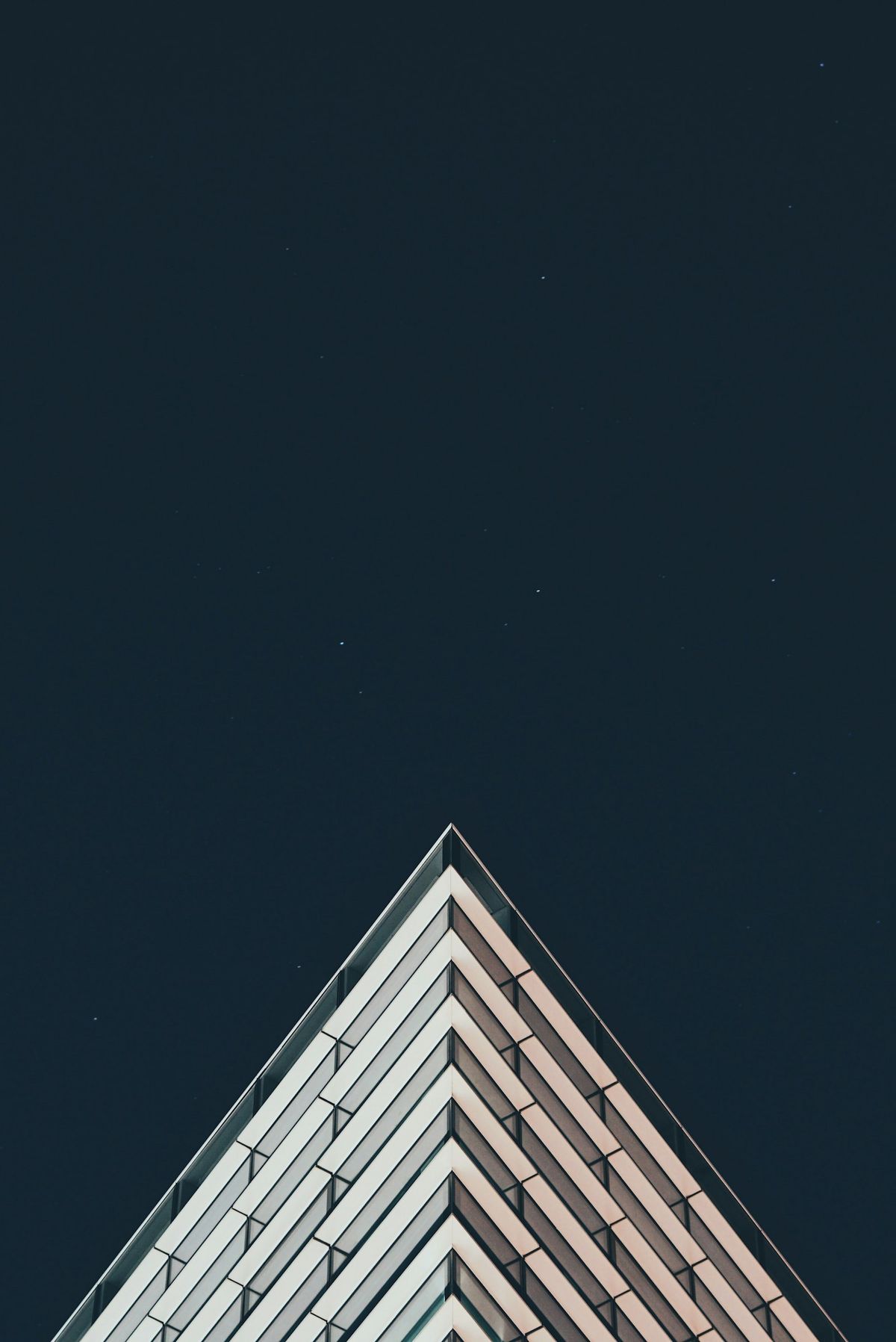 The point of a white tower rising into a dark blue sky