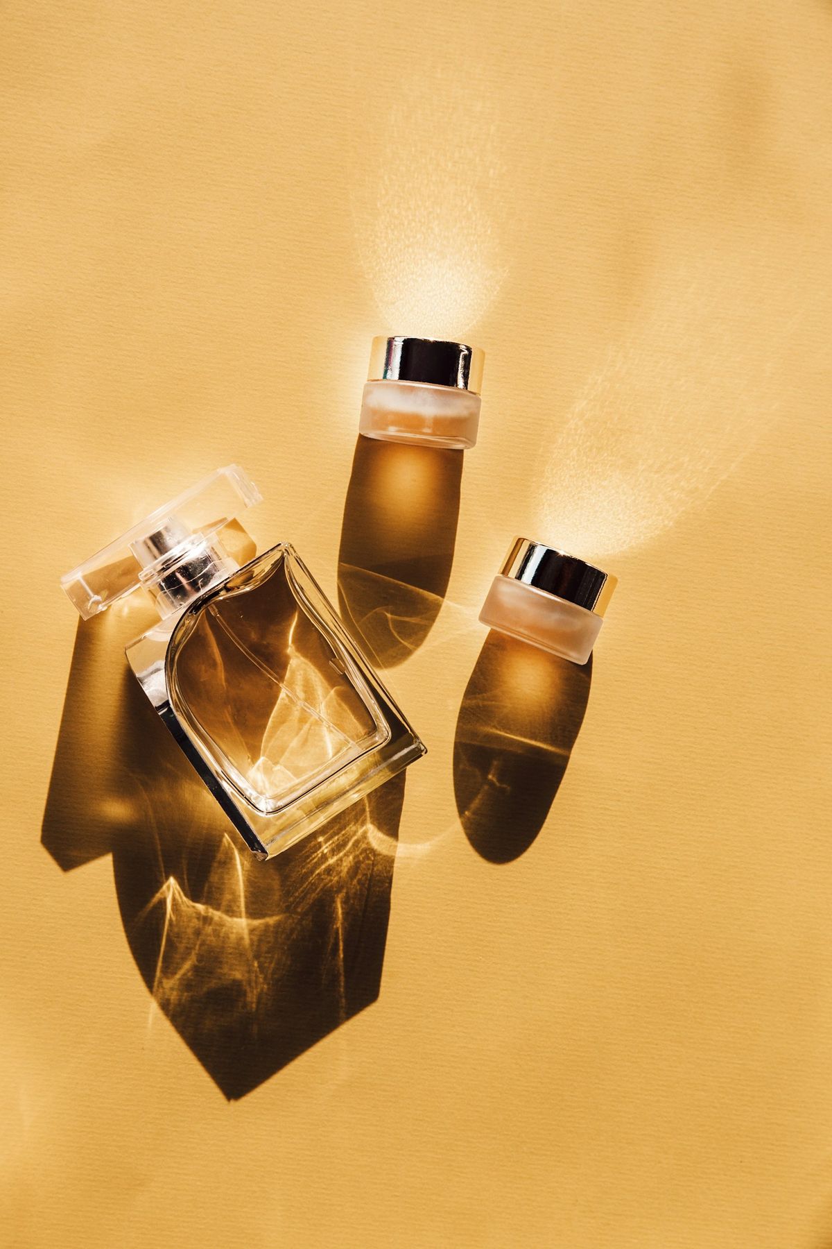 Small glass bottles lit from behind on a mustard backdrop